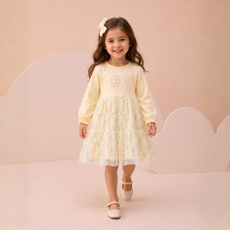 Girl wearing a long-sleeve dress with floral tulle skirt and bow hair accessory
