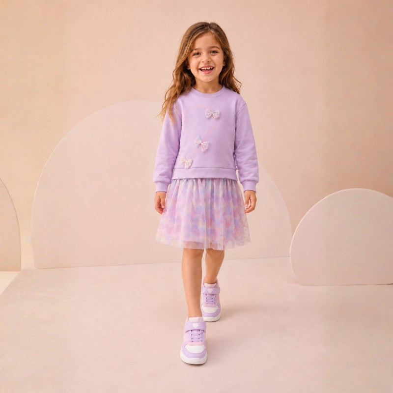 Girl wearing a lavender long-sleeve dress with butterfly details and a pastel tulle skirt