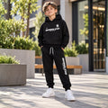 Young boy wearing a black kids fleece hoodie and matching jogger pants set 