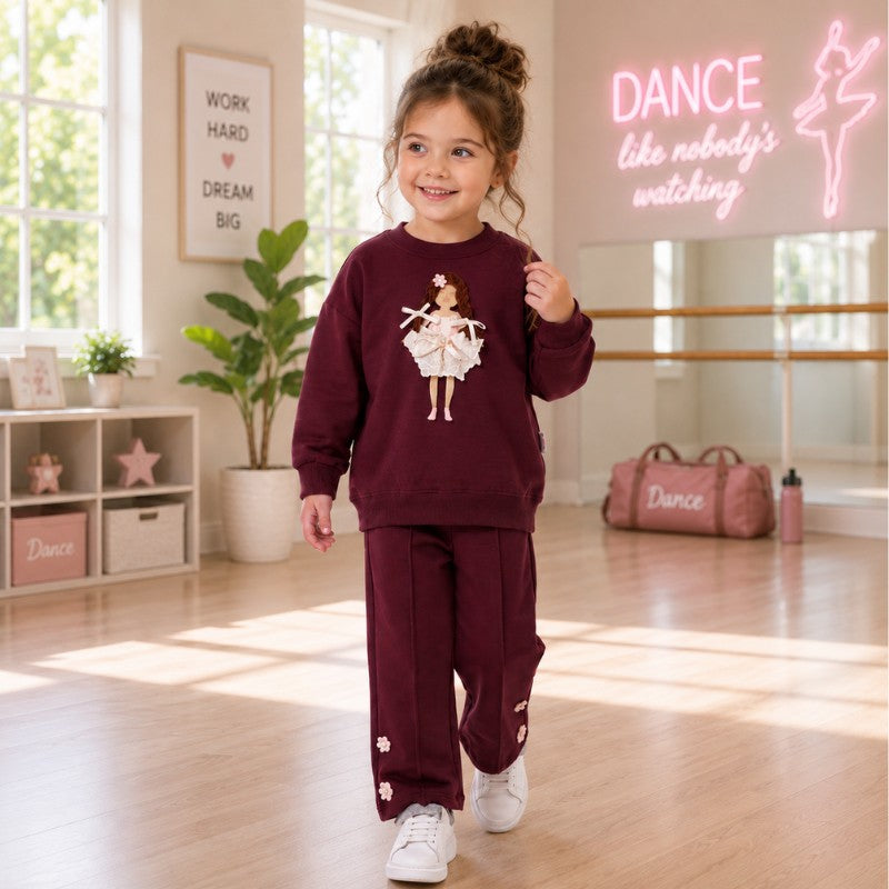 Young girl wearing a burgundy ballerina sweatshirt and matching pants in a dance studio