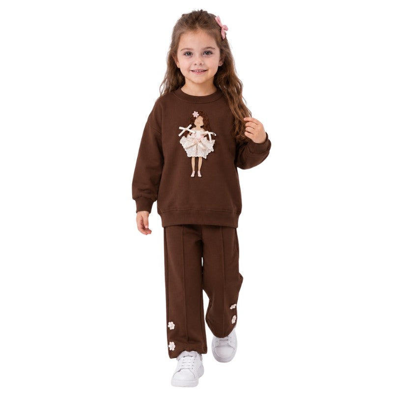 Young girl wearing a brown ballerina sweatshirt and matching pants in a dance studio