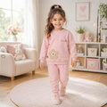 Smiling young girl wearing a pink floral sweatshirt and matching jogger tracksuit 