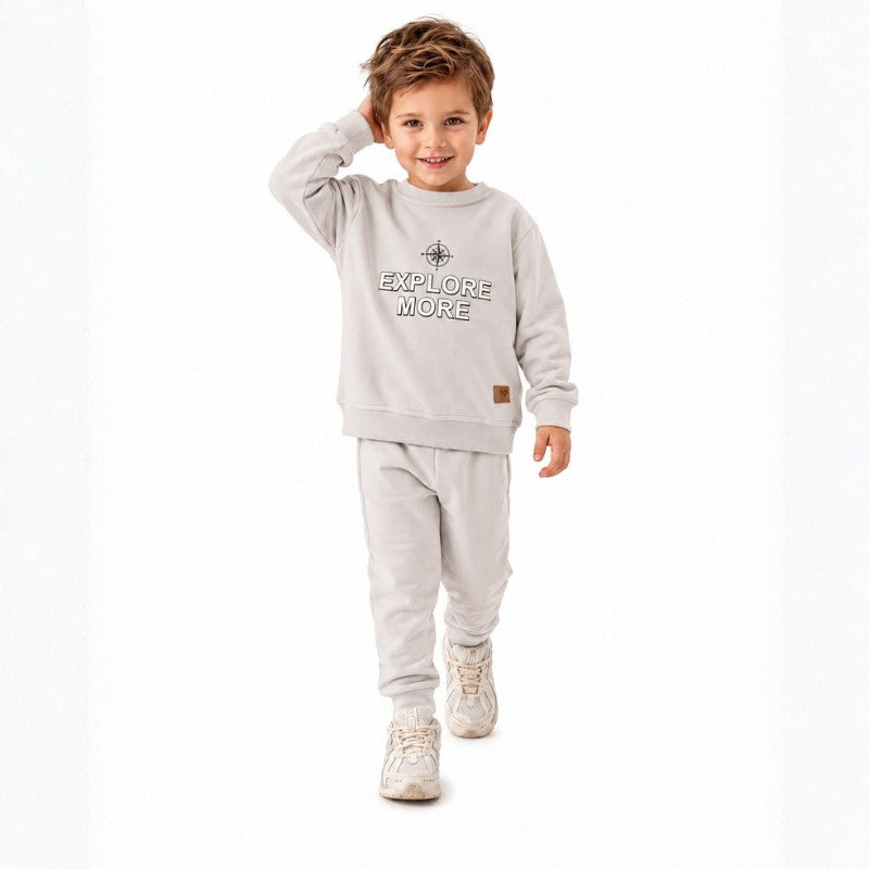 Smiling young boy wearing a  “Explore More” sweatshirt with matching jogger pants 