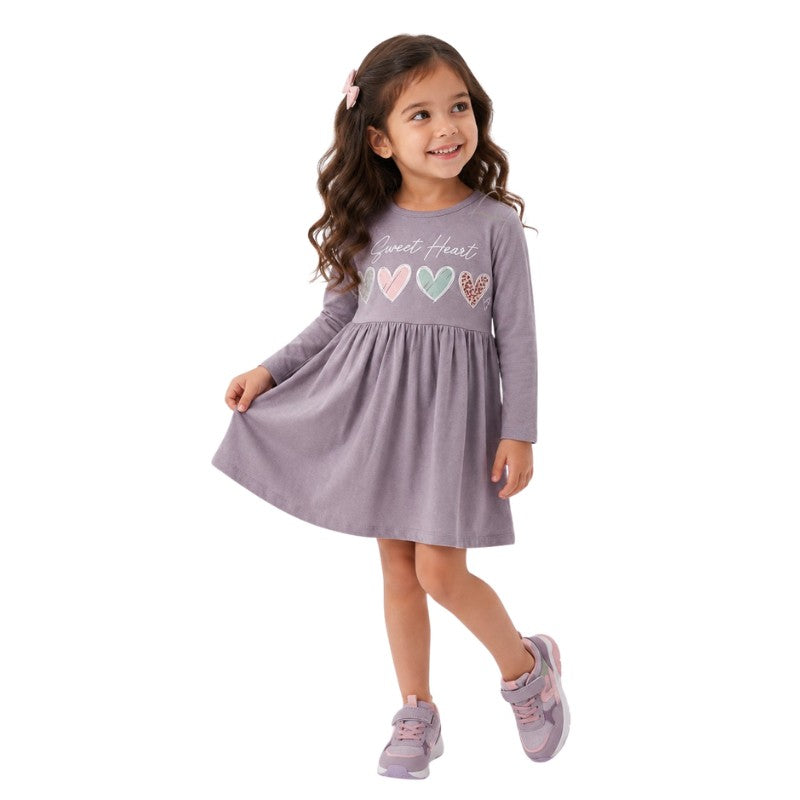 Young girl wearing a long sleeve dress with colorful heart prints