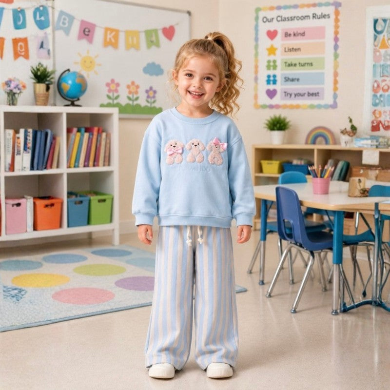 Young girl wearing a teddy bear sweatshirt with striped pants 