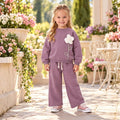 Girl wearing a mauve flower appliqué sweatshirt and matching wide-leg pants 