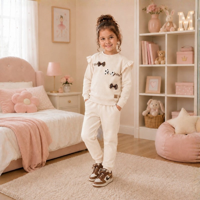 Girl wearing a ivory cream bow-detail sweatshirt and matching jogger pants tracksuit set