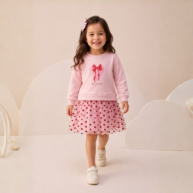 Girl wearing a  bow sweatshirt and red heart-print tulle skirt