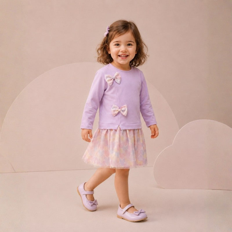 Toddler girl wearing a long-sleeve dress with bow details and a pastel tulle skirt