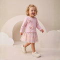 Toddler girl wearing a long-sleeve dress with bow details and a pastel tulle skirt