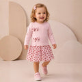 Toddler girl wearing a long-sleeve dress with bow details and a red heart-print tulle skirt