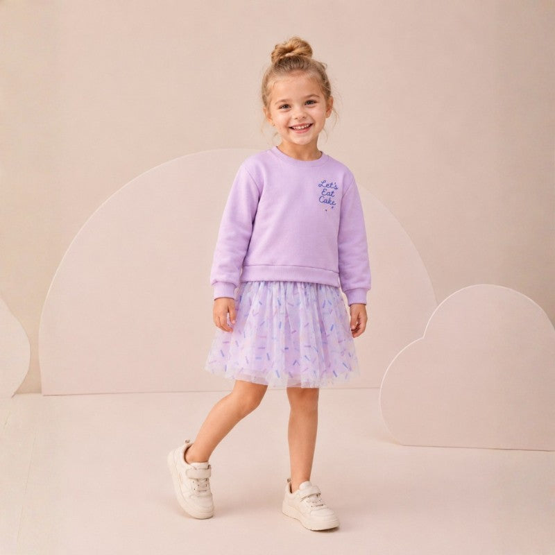 Girl wearing a lavender long-sleeve dress with “Let’s Eat Cake” print and a tulle skirt