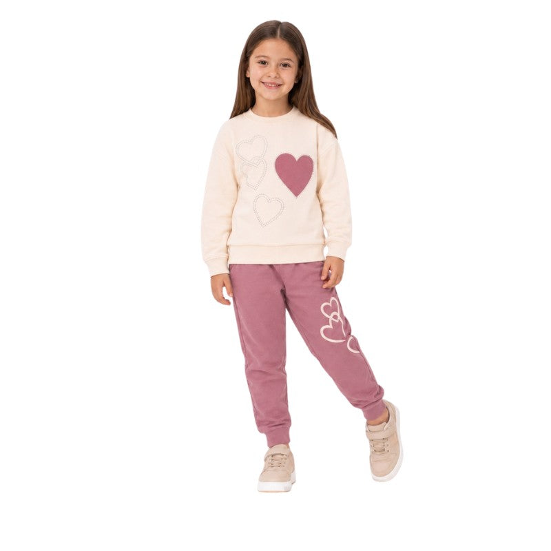 Young girl wearing a cream heart-print sweatshirt and dusty pink jogger pants 