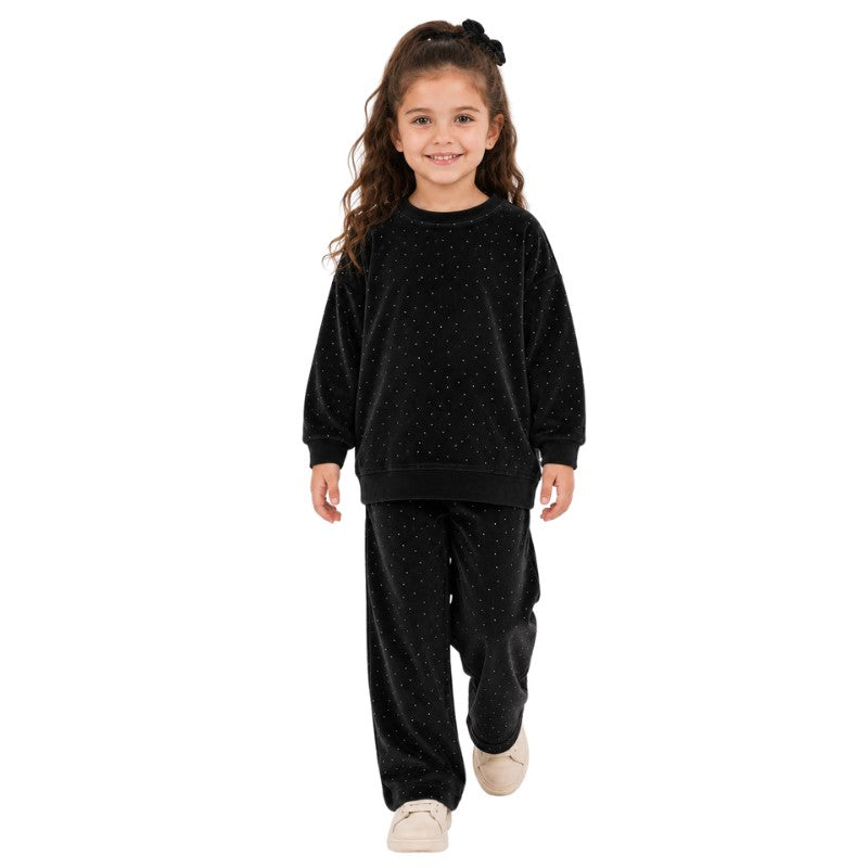 Young girl wearing a black polka dot sweatshirt and matching pants.