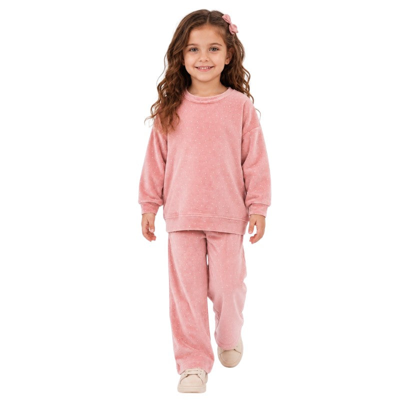 Young girl wearing a pink polka dot sweatshirt and matching pants.