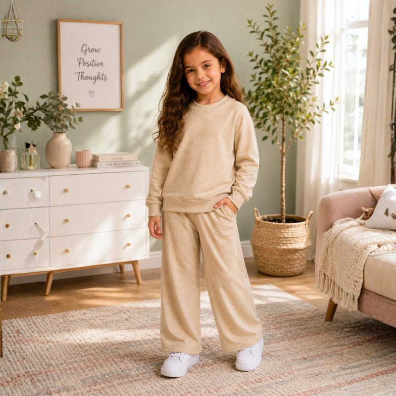 Young girl wearing a beige polka dot sweatshirt and matching wide-leg pants while painting in an art studio.