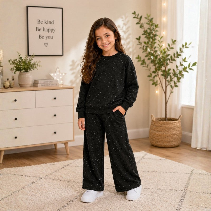 Young girl wearing a black polka dot sweatshirt and matching wide-leg pants while painting in an art studio.