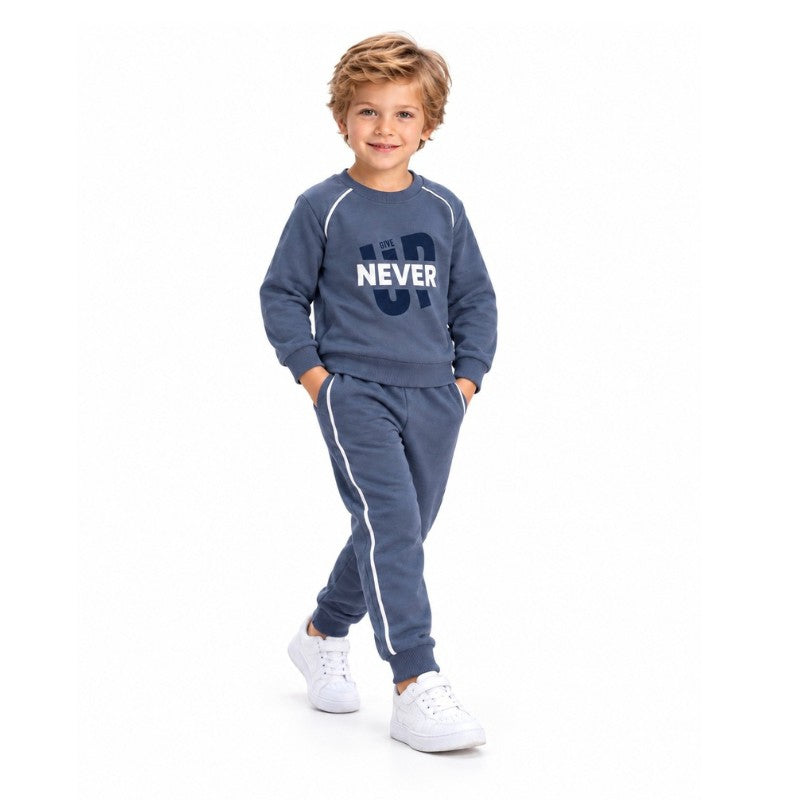 Young boy wearing a blue Never Give Up sweatshirt with matching jogger pants and sporty side stripes, a casual kids tracksuit set