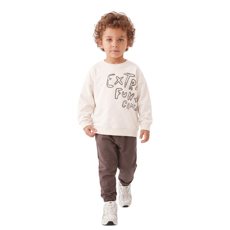 Young boy wearing graphic sweatshirt and brown jogger pants.