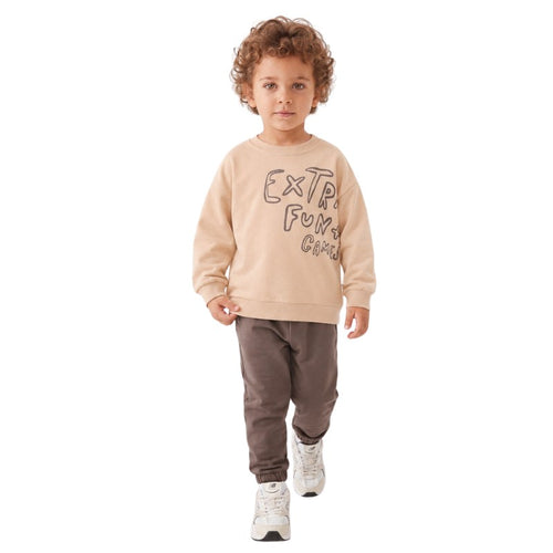 Young boy wearing a graphic sweatshirt, brown jogger pants