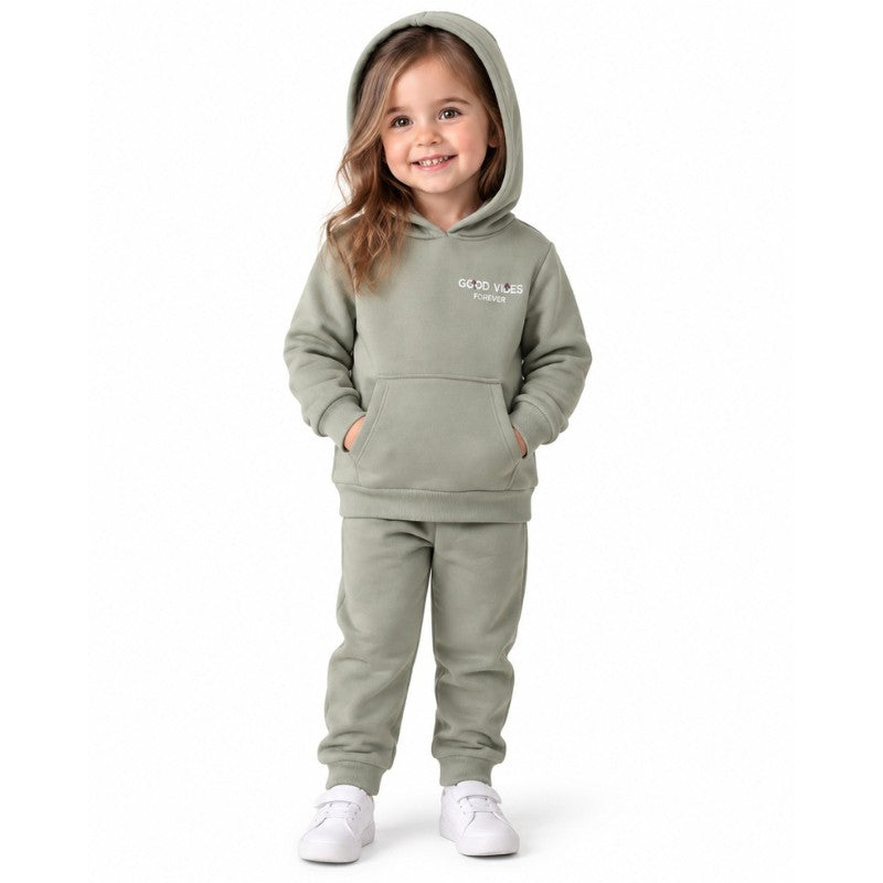 Young girl wearing a sage green slogan hoodie with a kangaroo pocket and matching cuffed joggers.