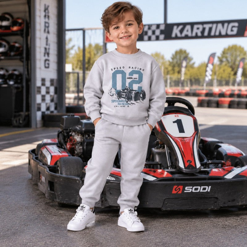 Young boy wearing a grey racing sweatshirt and jogger set 