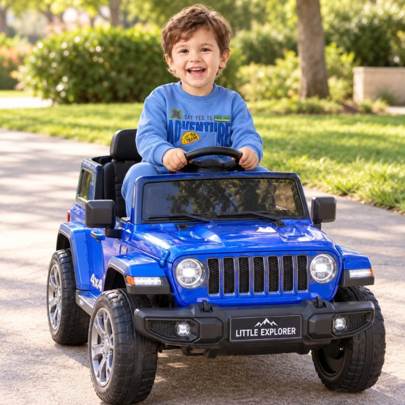 Young boy wearing a blue adventure sweatshirt playing in a toy car outdoors