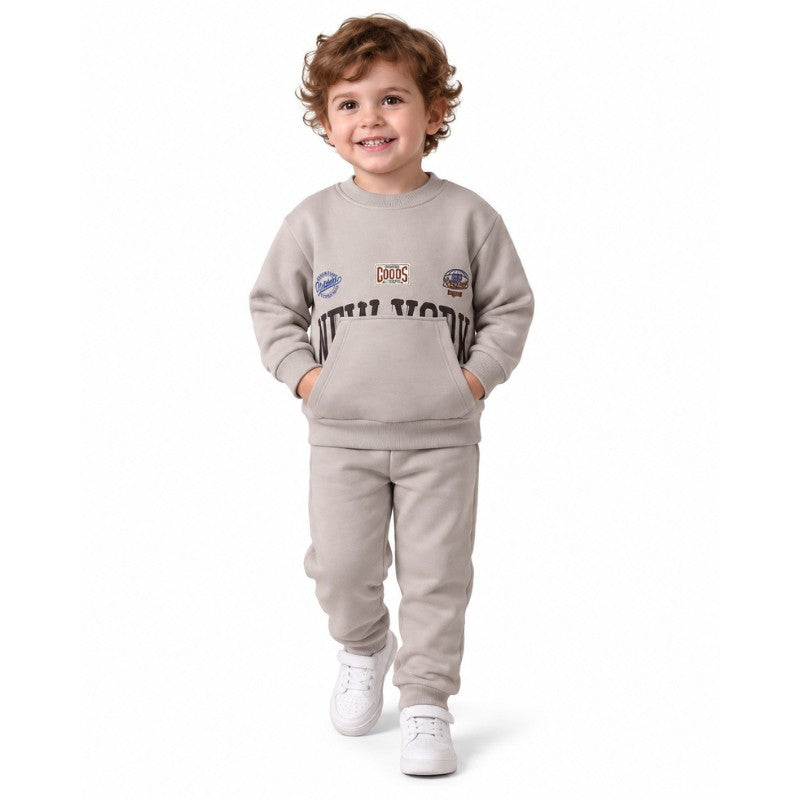 Young boy wearing a beige sweatshirt and jogger set with white sneakers