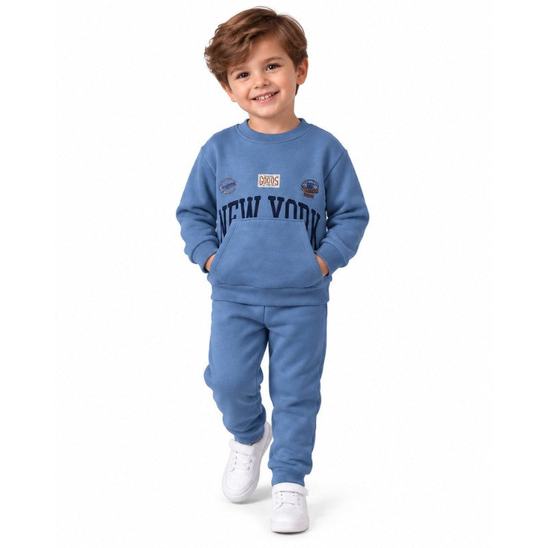 Young boy wearing a blue sweatshirt and jogger set with white sneakers