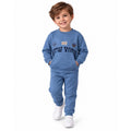 Young boy wearing a blue sweatshirt and jogger set with white sneakers