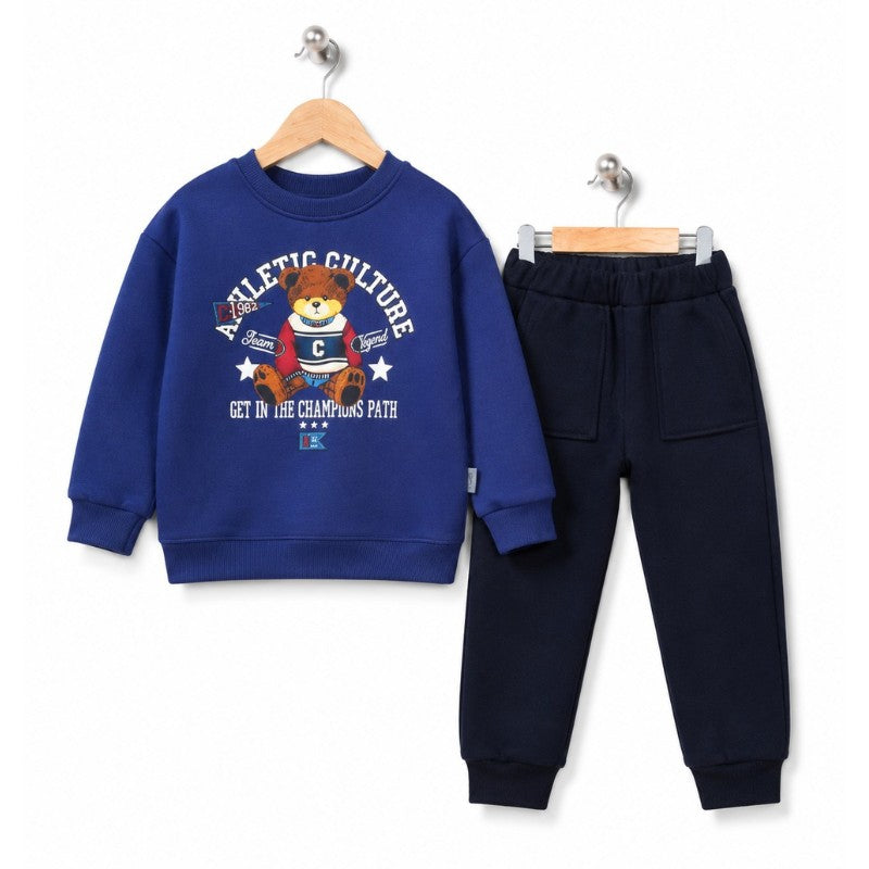 Young boy wearing a blue teddy bear sweatshirt and navy pants 