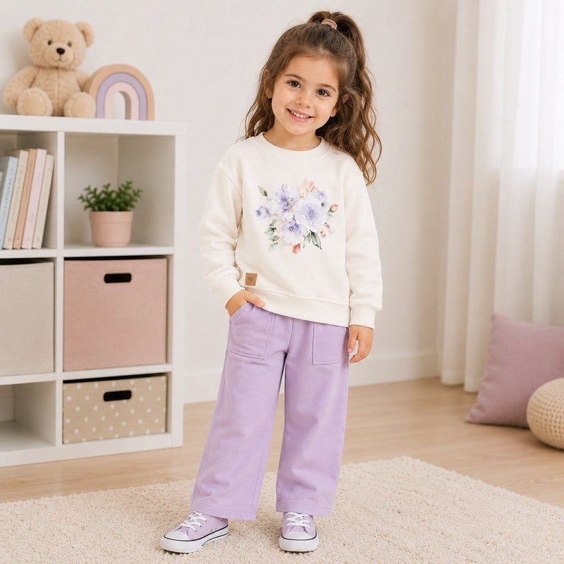 Girl wearing a cream floral sweatshirt with wide-leg pants 