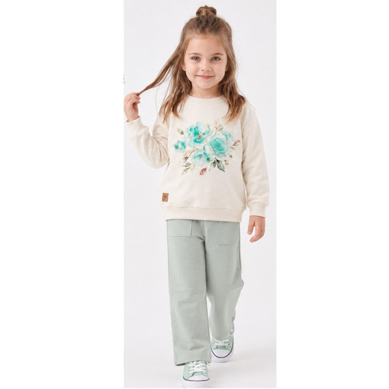 Girl wearing a cream floral sweatshirt with wide-leg pants 