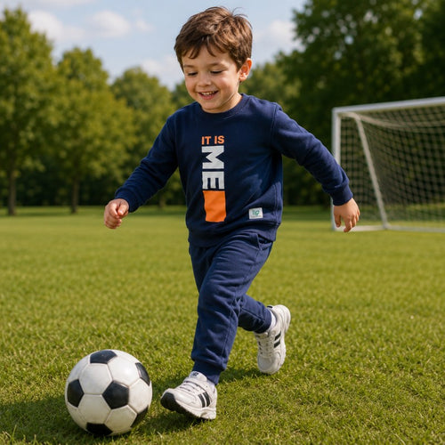 Smiling young boy wearing a “It Is Me” graphic sweatshirt with matching jogger pants 