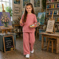 Young girl wearing a blush pink polka dot sweatshirt and matching wide-leg pants while painting in an art studio.