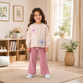 
Young girl wearing a cream floral sweatshirt with dusty pink wide-leg pants 