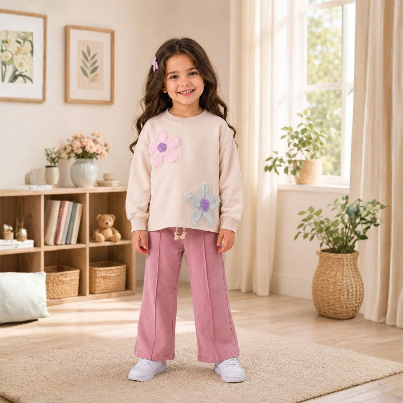 
Young girl wearing a cream floral sweatshirt with dusty pink wide-leg pants 