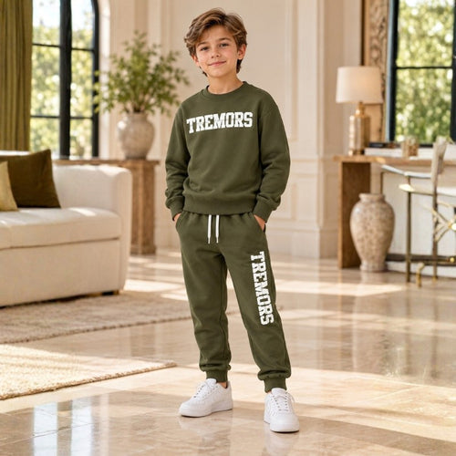 Boy wearing an olive TREMORS sweatshirt and matching joggers with white trainers in an elegant cream interior.