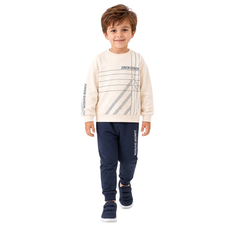 Young boy wearing a cream graphic sweatshirt and jogger pants.