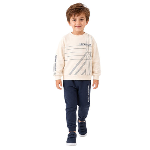 Young boy wearing a cream graphic sweatshirt and jogger pants.