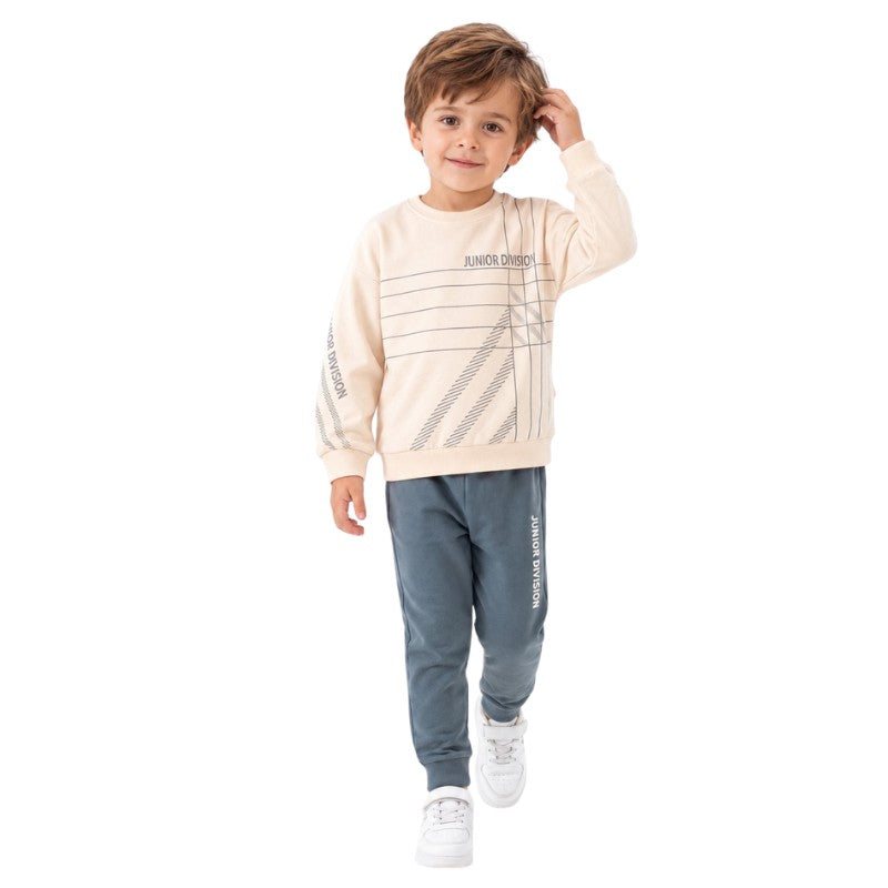 Young boy wearing a cream graphic sweatshirt and jogger pants.